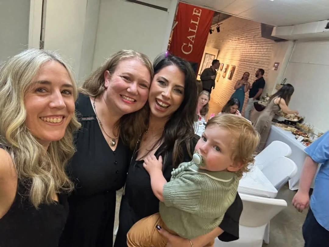Three women and a child smiling together for a gallery selfie.
