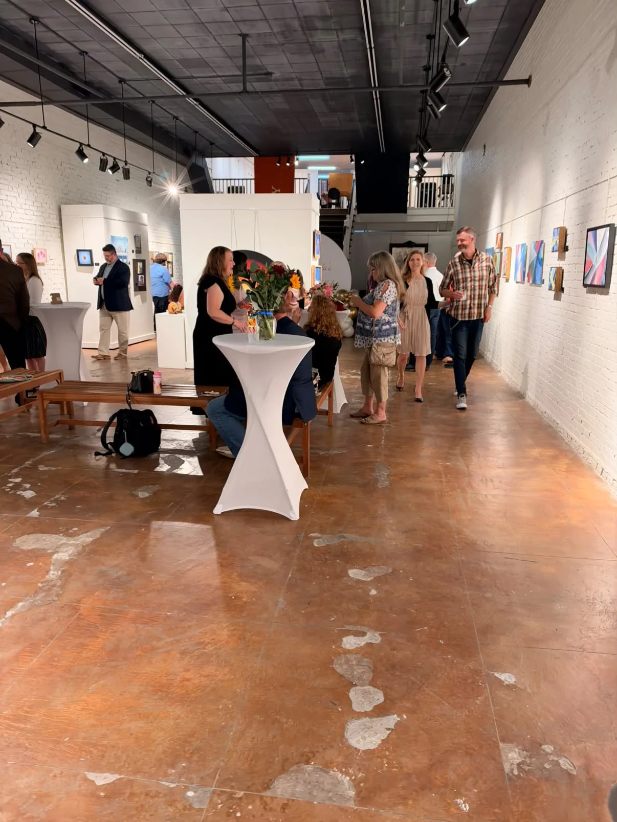 Guests gathered around flower arrangements in the gallery.