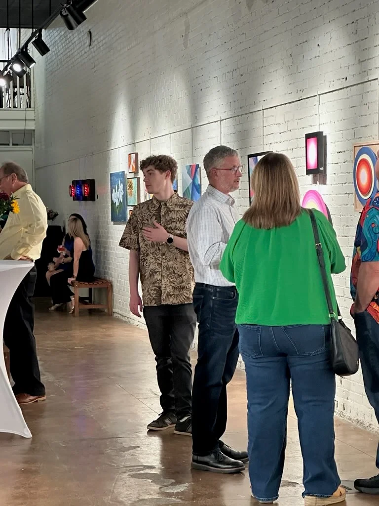 Guests talking beside a wall of colorful paintings.