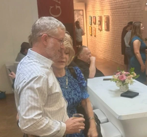 Two guests talking beside the refreshment table and a flower arrangement.