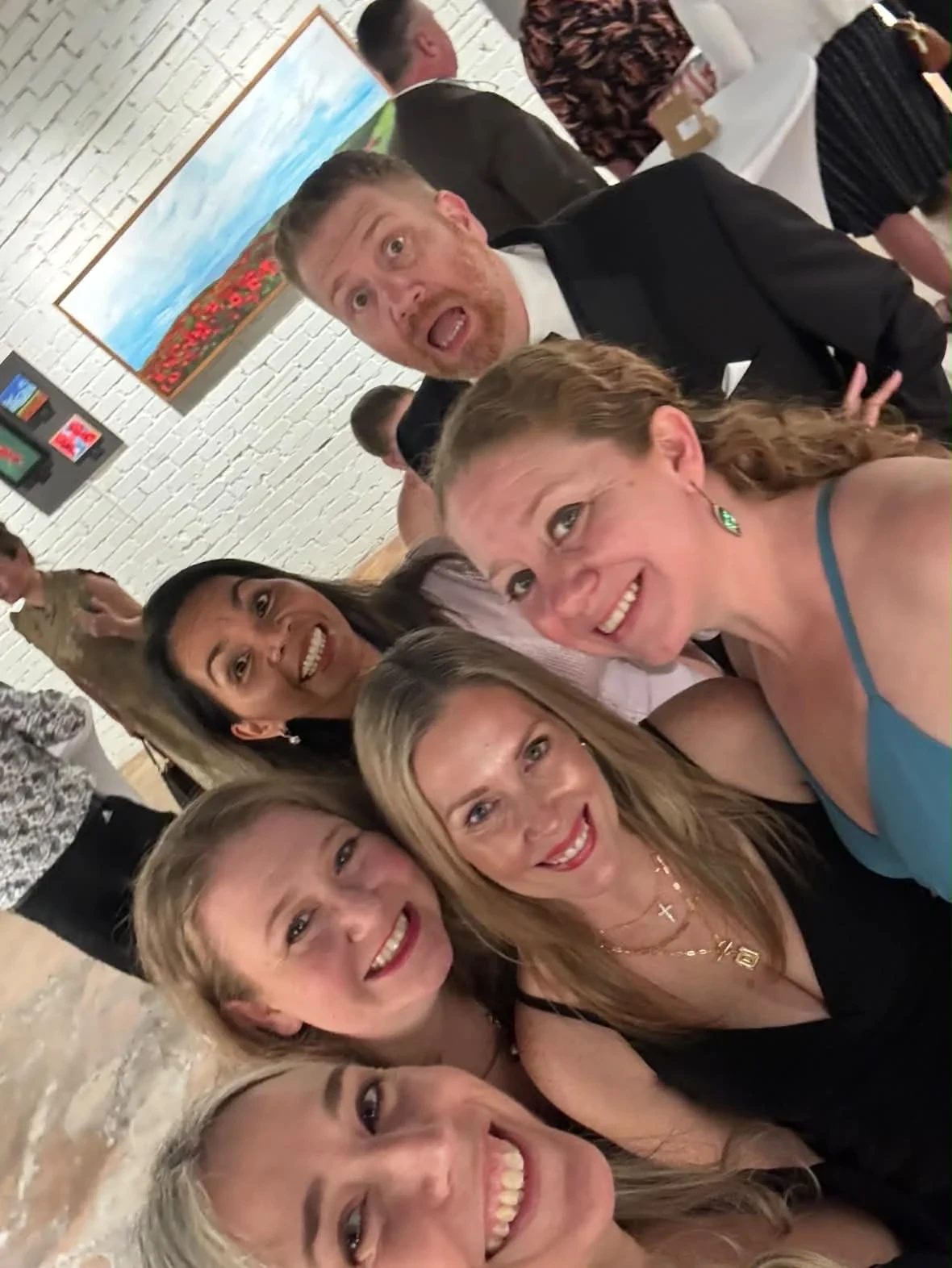 A group of guests smiling together for a gallery selfie.