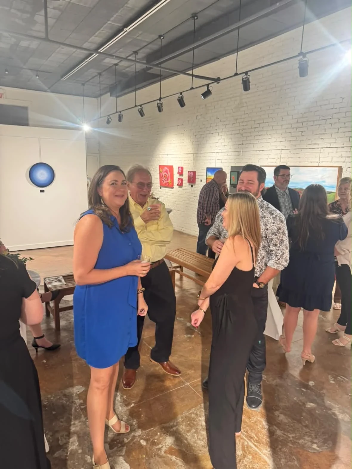 Guests in conversation with paintings along the gallery wall.
