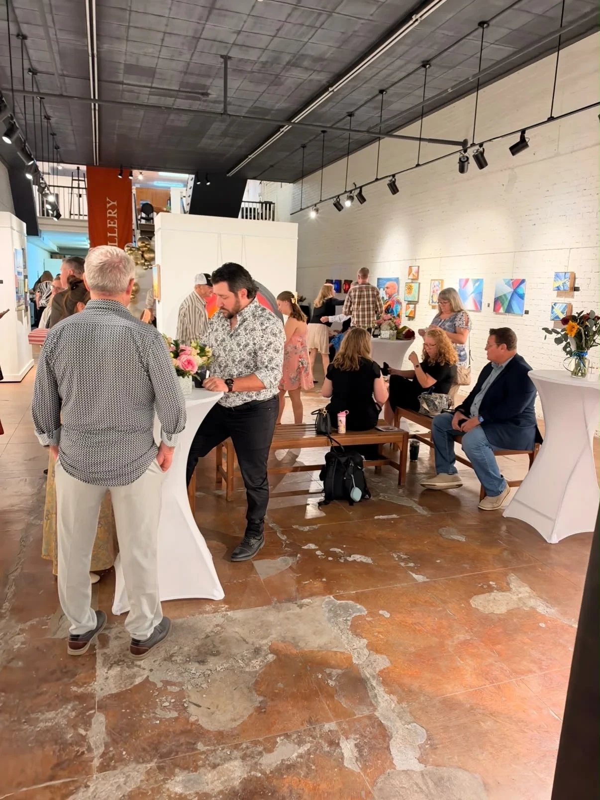 Guests talking and enjoying the paintings in the gallery.