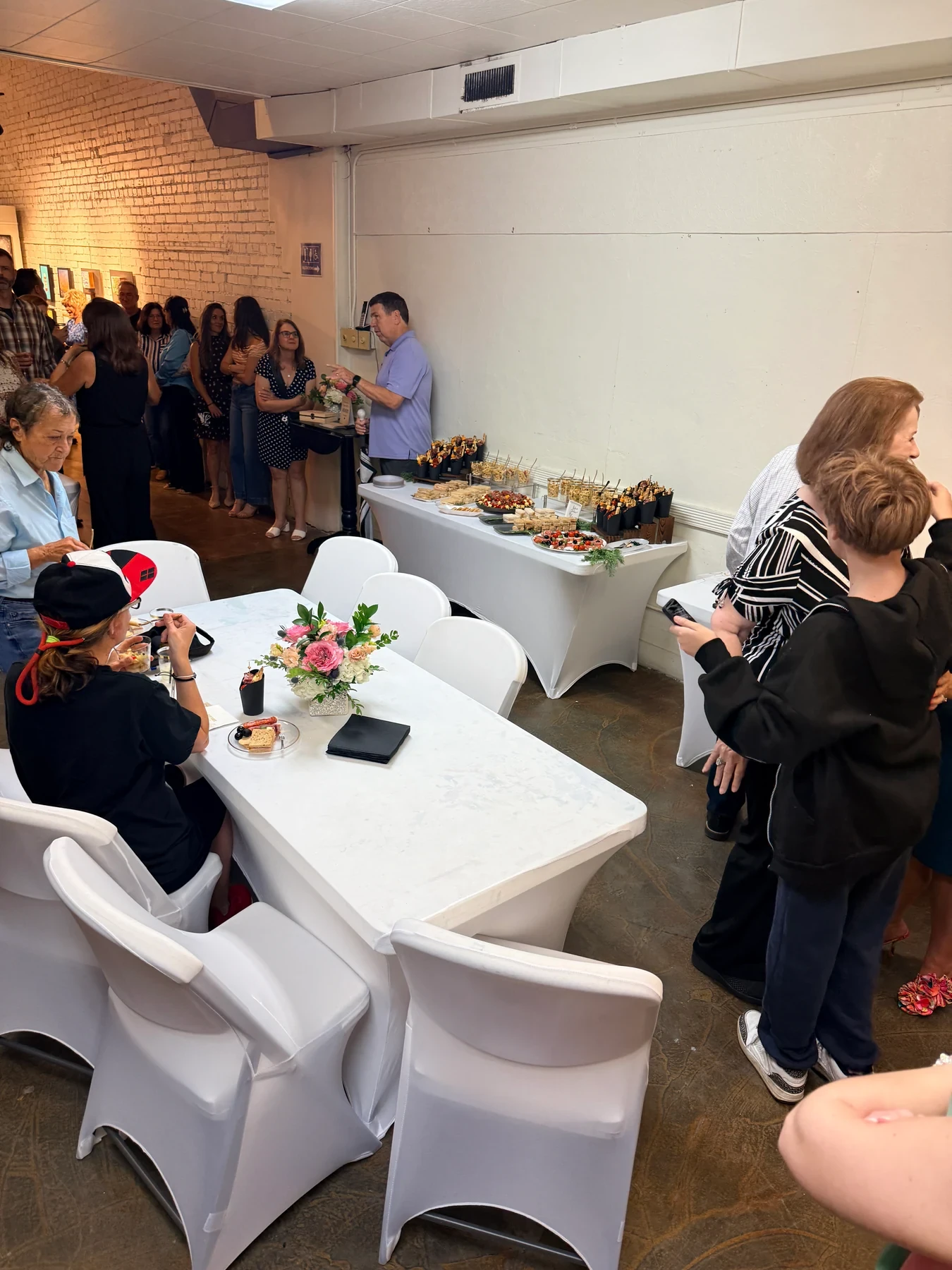 Guests gathered around the refreshment tables with food and flowers.