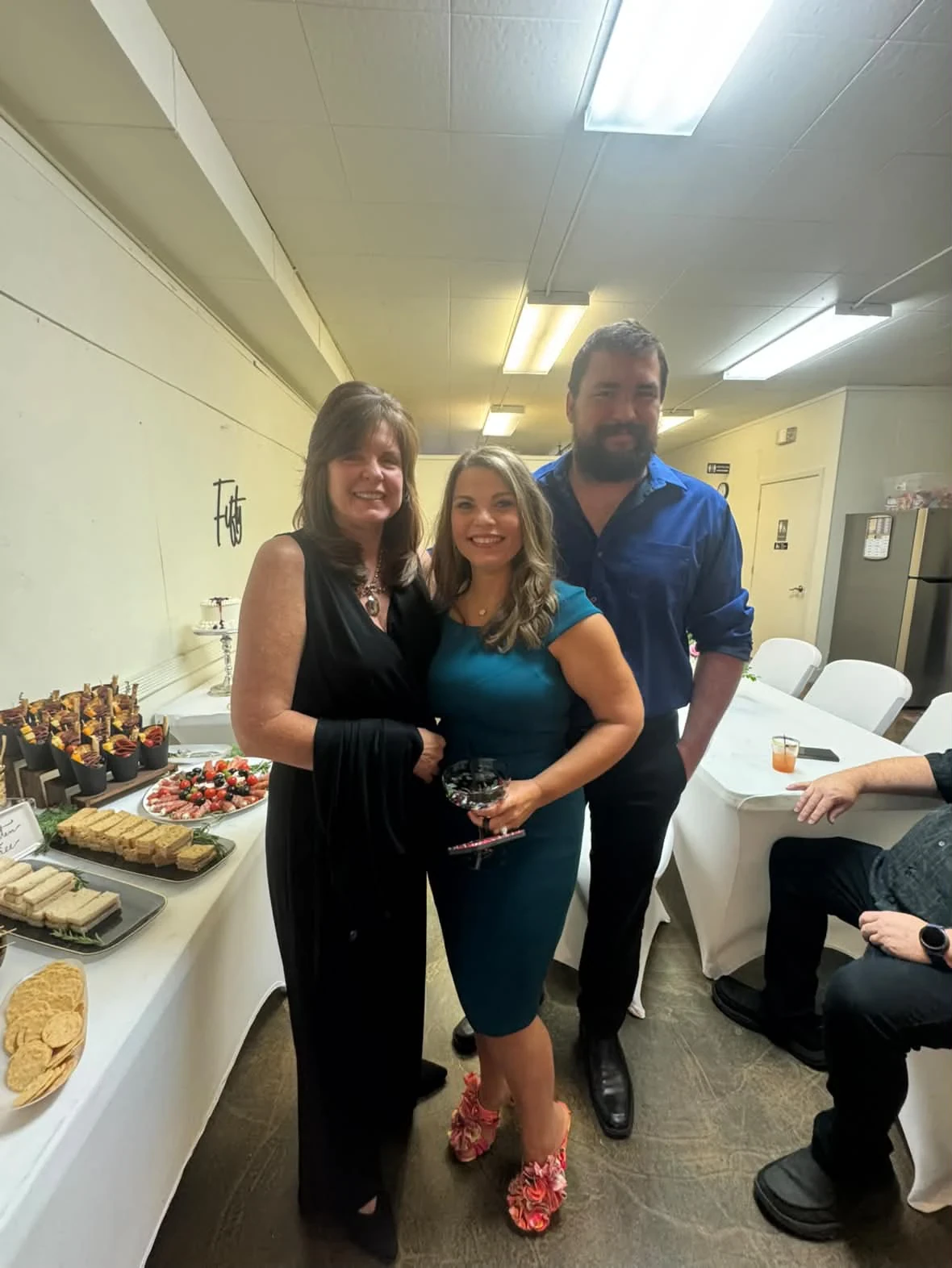 Angela posing with two guests beside the food table.