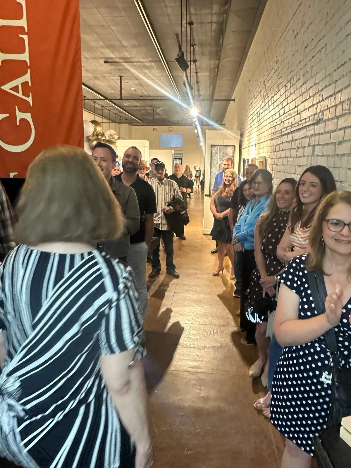 Guests smiling and gathering along the gallery wall during the celebration.
