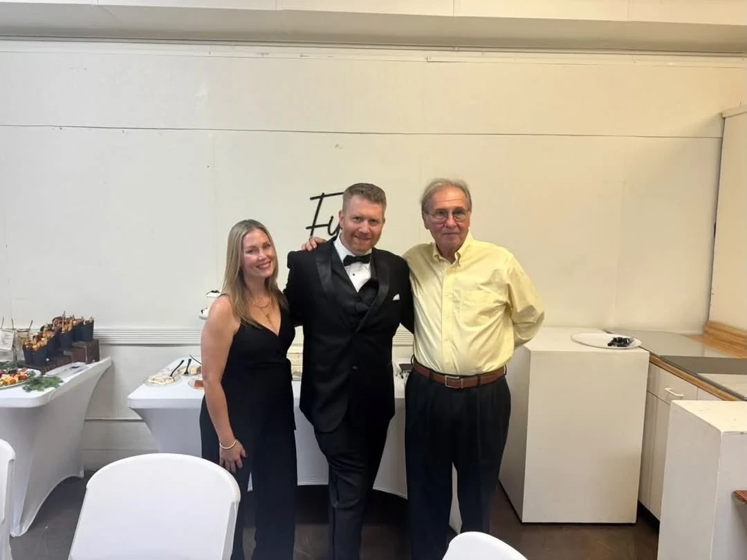 Three guests posing together beside the refreshment tables.